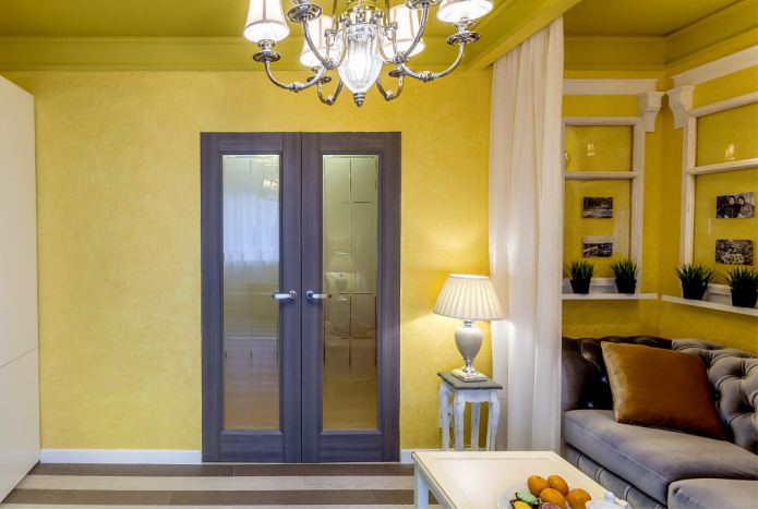 una combinazione di pareti gialle con una porta marrone scuro con inserti in vetro
