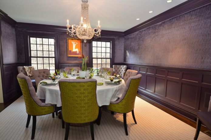 salle à manger avec papier peint violet foncé et chaises vertes et violettes