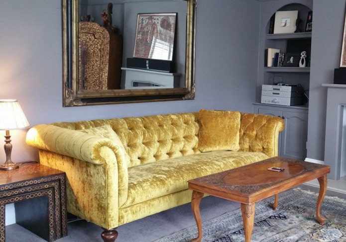 dzeltens Česterfīldas dīvāns interjerā