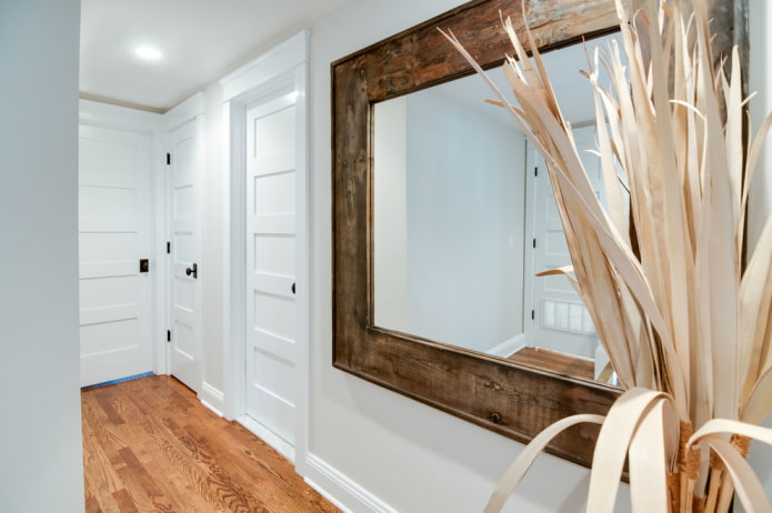 um espelho em uma moldura de madeira no interior do corredor