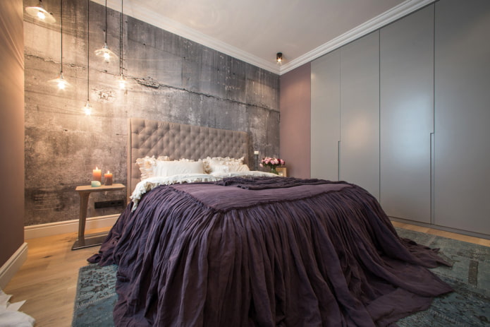 gulta ar violetu gultas pārklāju guļamistabā