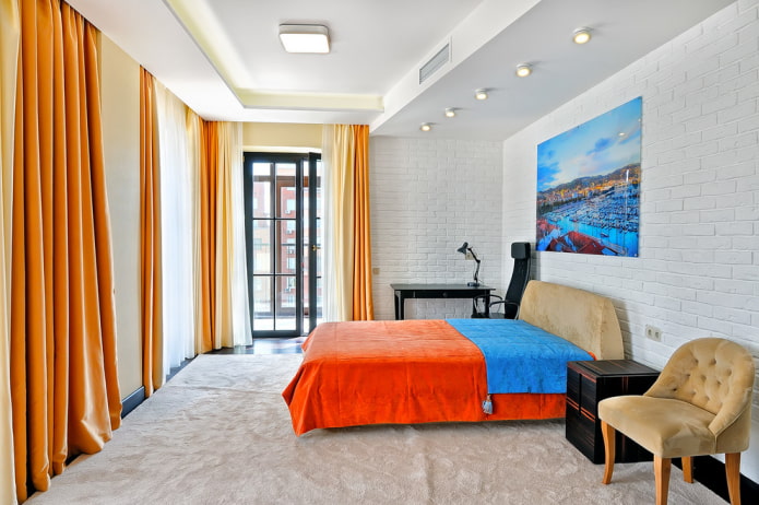 säng med orange sängäcke i sovrummet