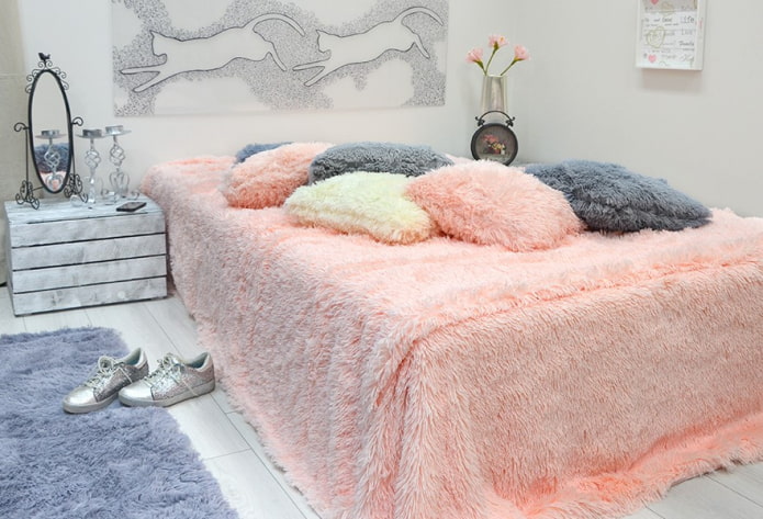 cama com um cobertor com uma pilha no quarto
