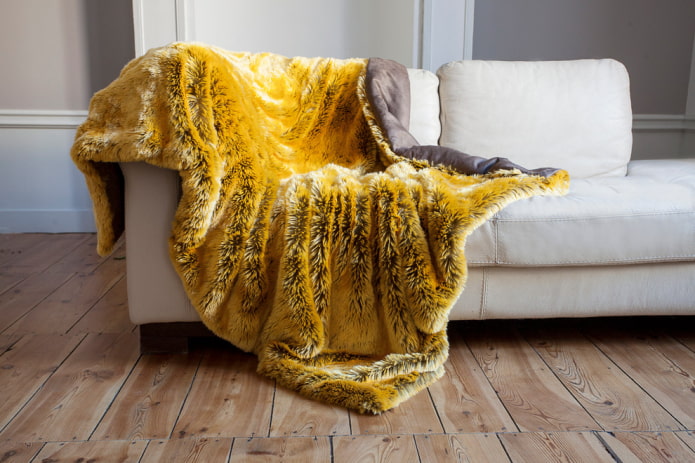 dzeltens gultas pārklājs dīvānam interjerā