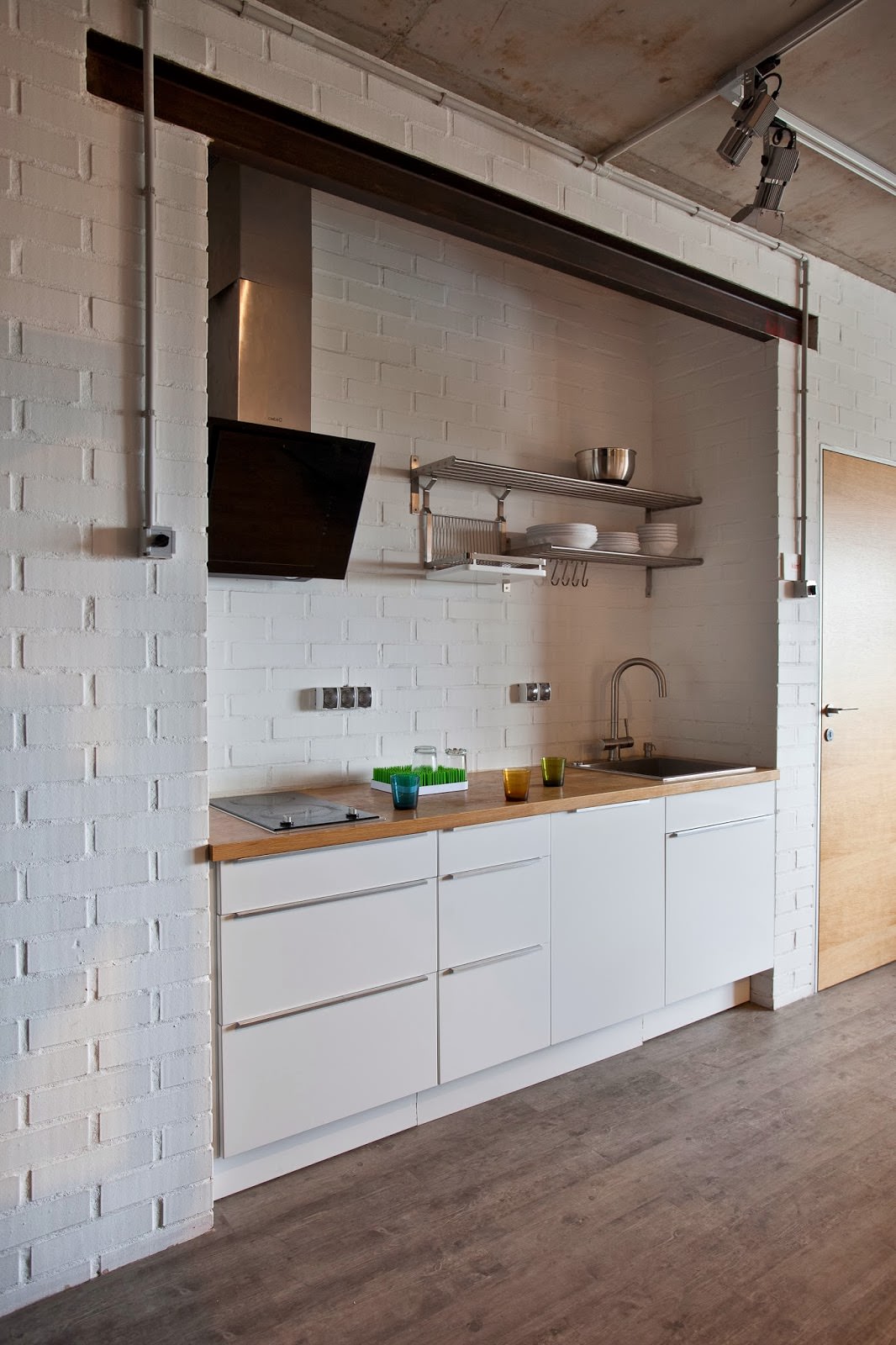 ห้องครัวพร้อมผนังอิฐสีขาวในการตกแต่งภายในของอพาร์ทเมนต์ที่สร้างสรรค์